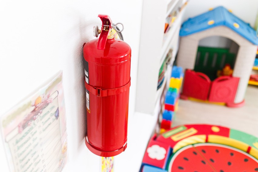 In einem Kindergarten hängt eine Feuerlöscher an der Wand eines Spielszimmers