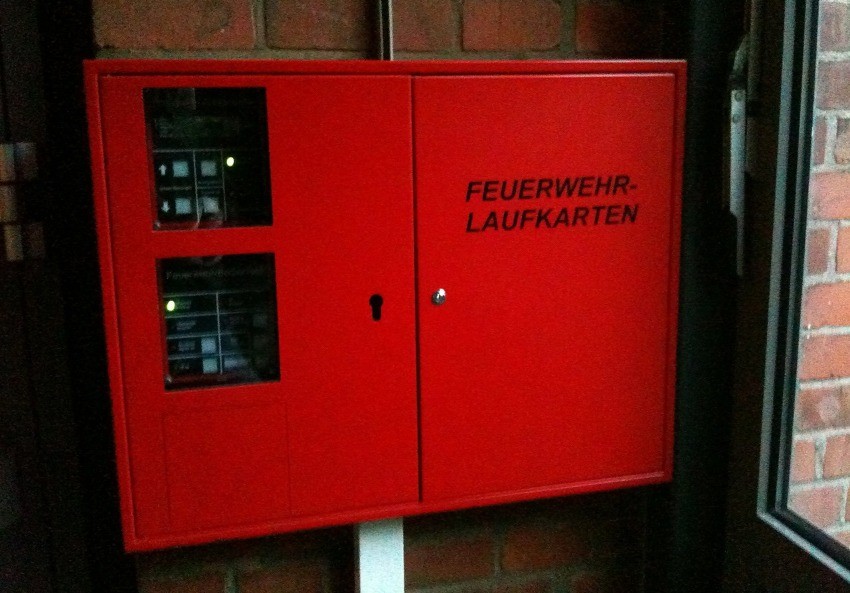 Erstinformationsstelle für die Feuerwehr mit Feuerwehrlaufkarten neben Feuerwehr-Anzeigetableau und Feuerwehr-Bedienfeld