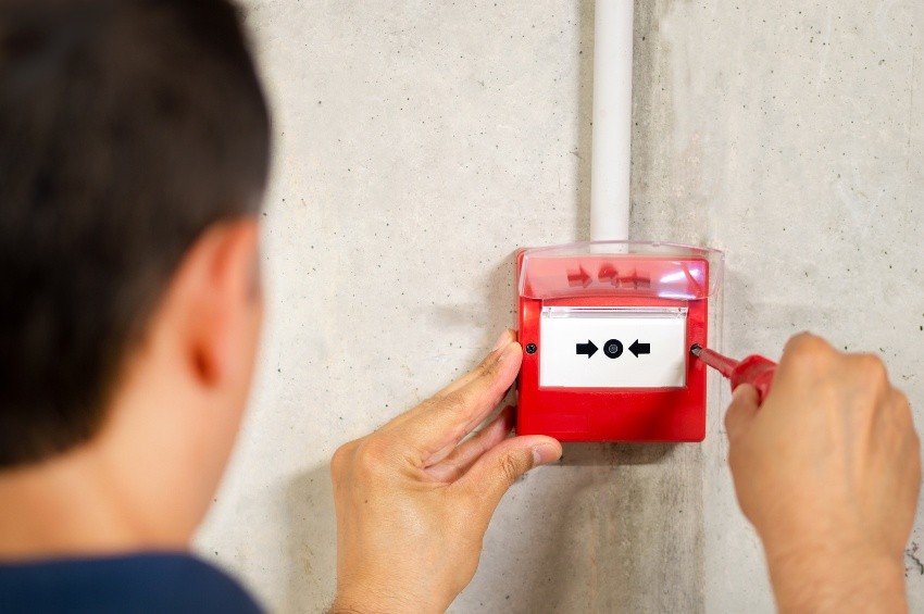 Mann installiert oder wartet manuellen Feueralarm - Meldertausch